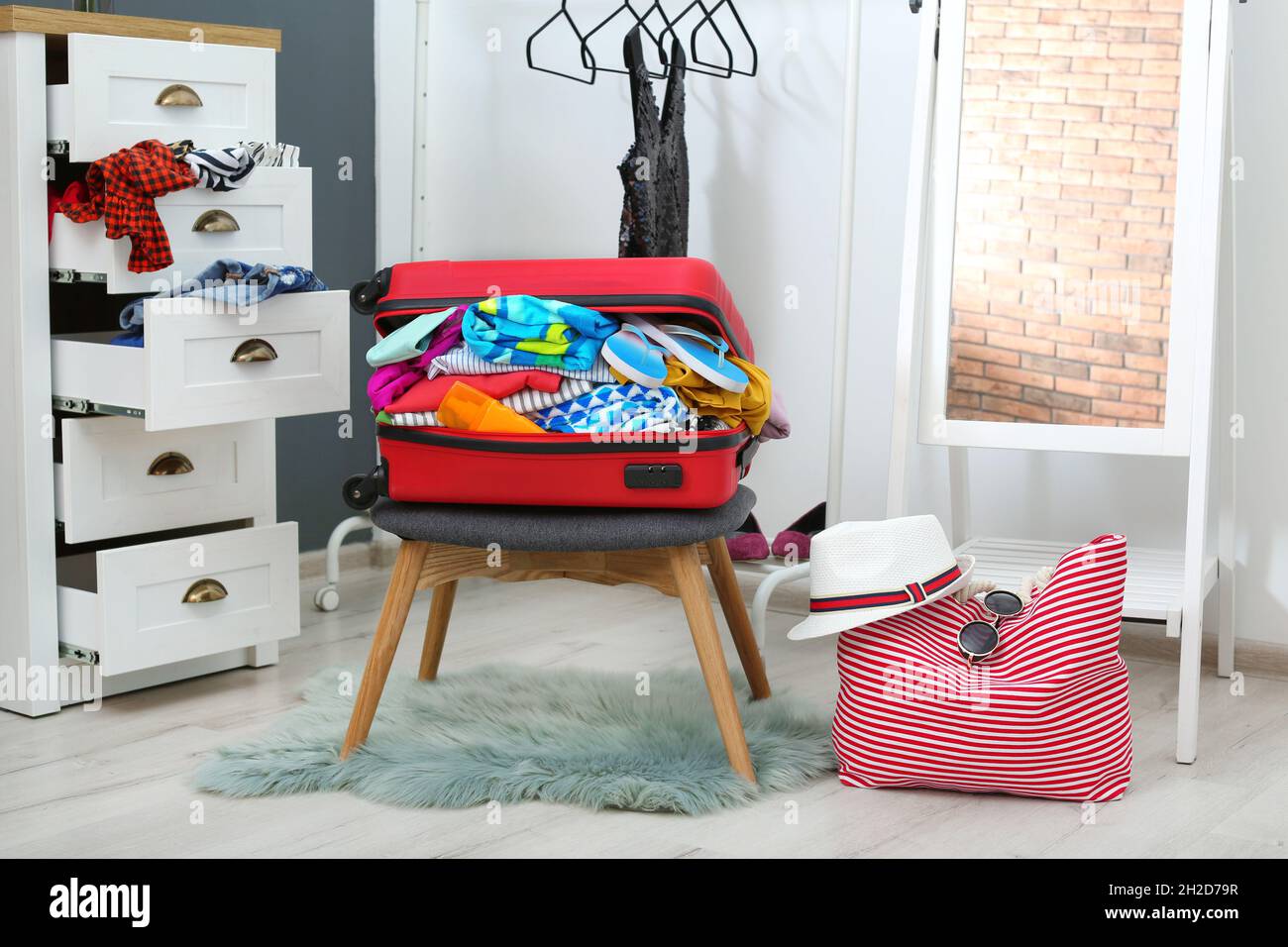 Maleta con ropa de playa y accesorios sobre taburete en el vestidor  Fotografía de stock - Alamy