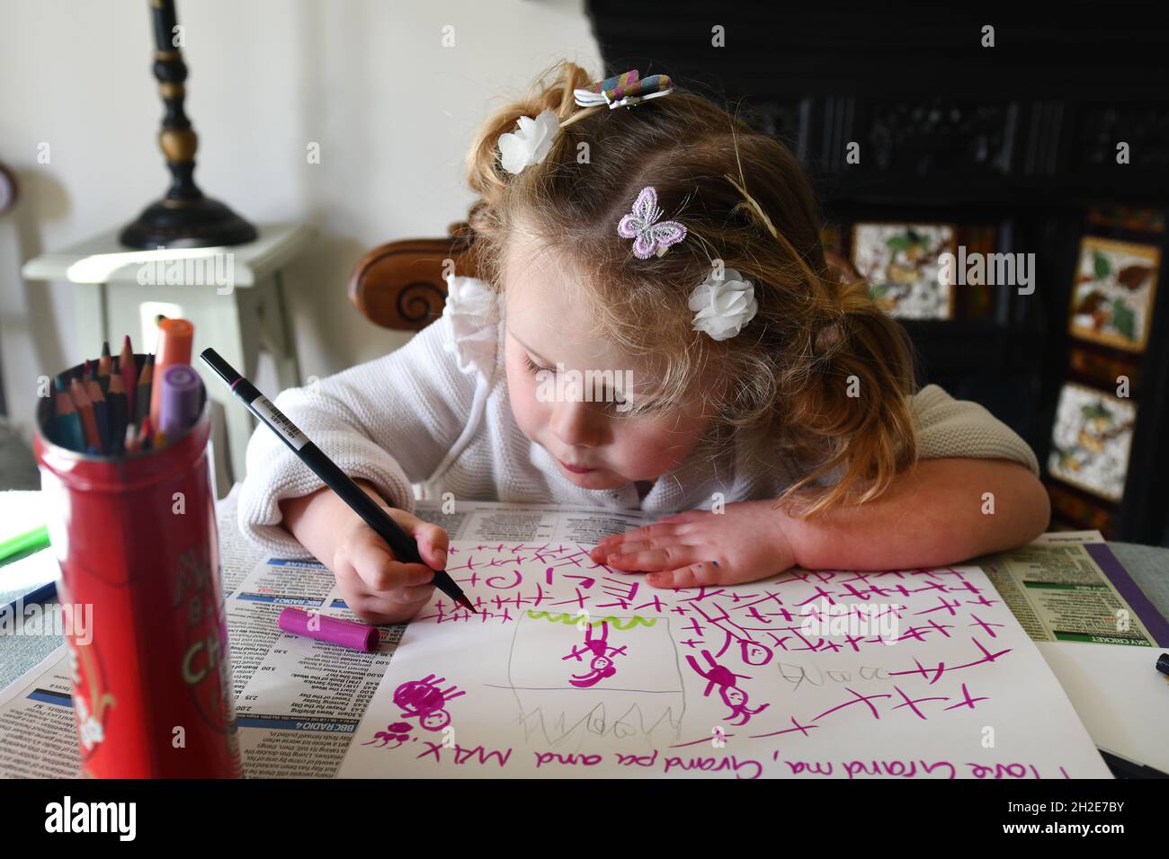 Niña pequeña escribiendo, dibujando y pintando en la escuela en casa Foto de stock