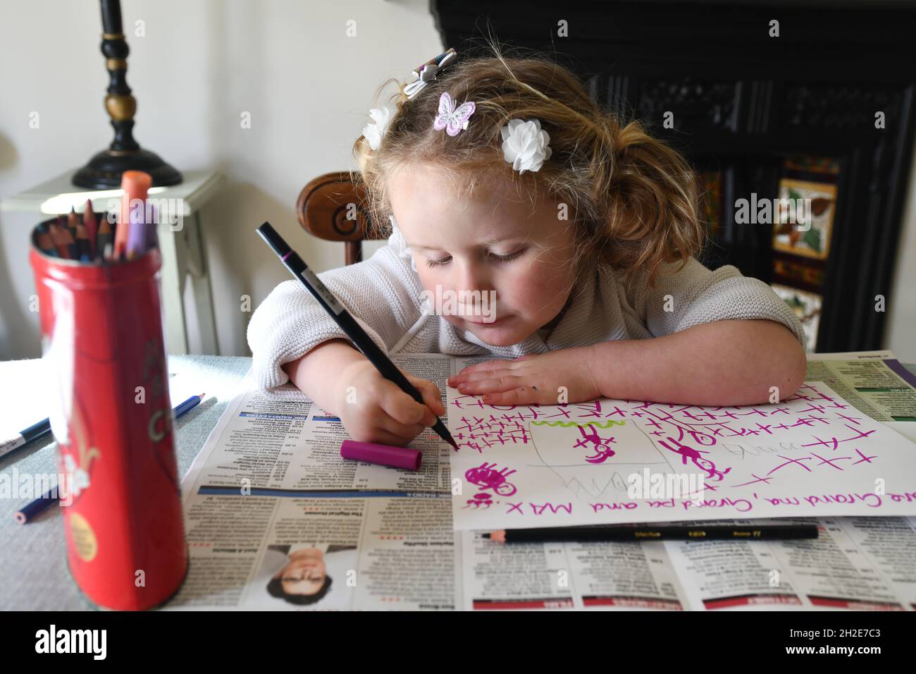 Niña pequeña escribiendo, dibujando y pintando en la escuela en casa Foto de stock