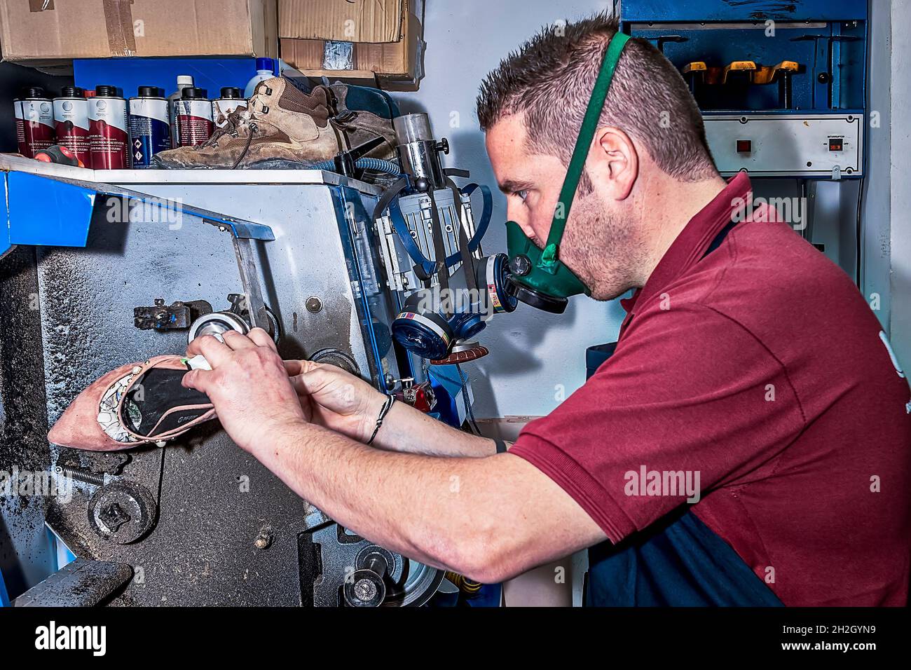 Zapatero joven mendando calzado en taller de reparación. Foto de stock