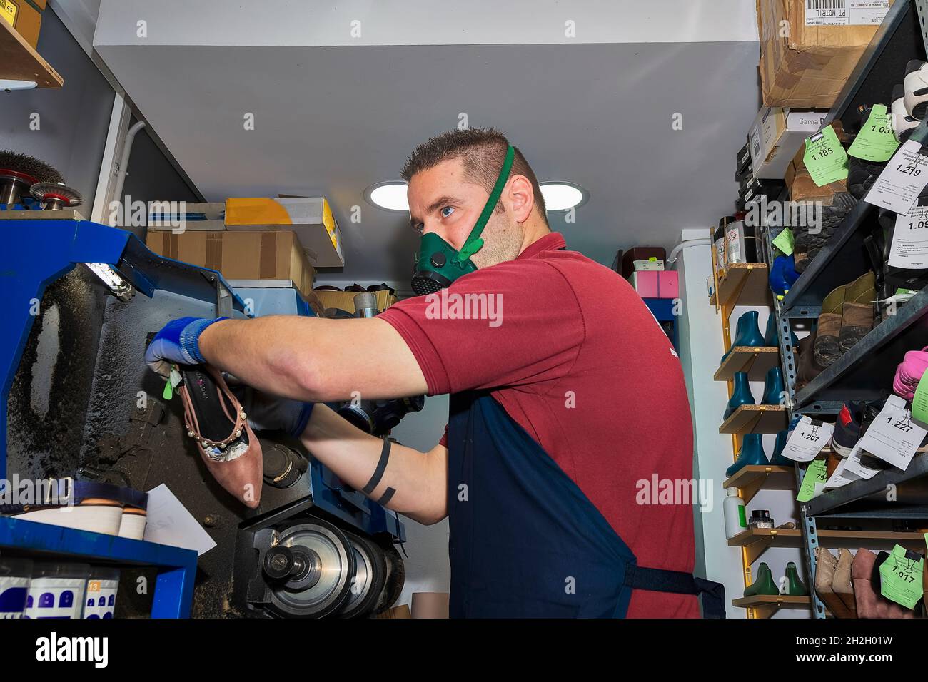 Zapatero joven mendando calzado en taller de reparación. Foto de stock