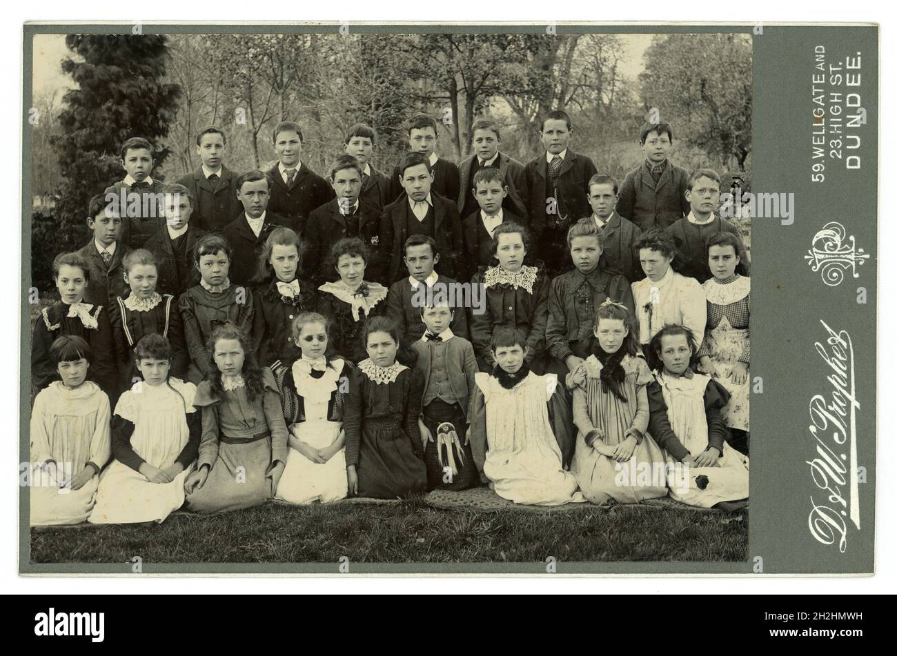 Original, clara tarjeta de gabinete victoriano del grupo de niños victorianos de la escuela, niños y niñas, de clase media bien vestido y uno de los niños lleva un reloj de bolsillo que era caro en ese momento. Posando para un grupo de retrato al aire libre. Muchas modas maravillosas de principios a finales de los años 1890 - vestidos de bata, y estilos de mangas hinchadas de 1893-98, del estudio de D. & W. Prophet, Dundee, Escocia, Reino Unido Foto tomada alrededor de 1898 Foto de stock