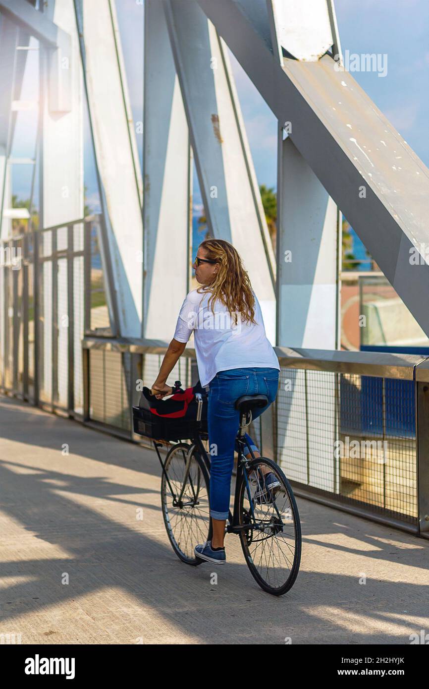 Atractiva mujer que va a un paseo casual en el puente de Parc Forum en su  bicicleta Fotografía de stock - Alamy