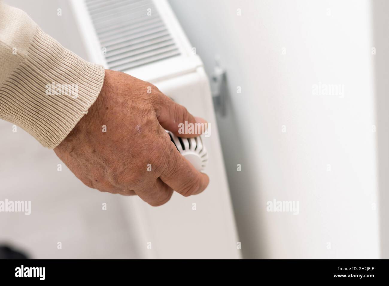 Un anciano se calienta las manos sobre un calentador eléctrico