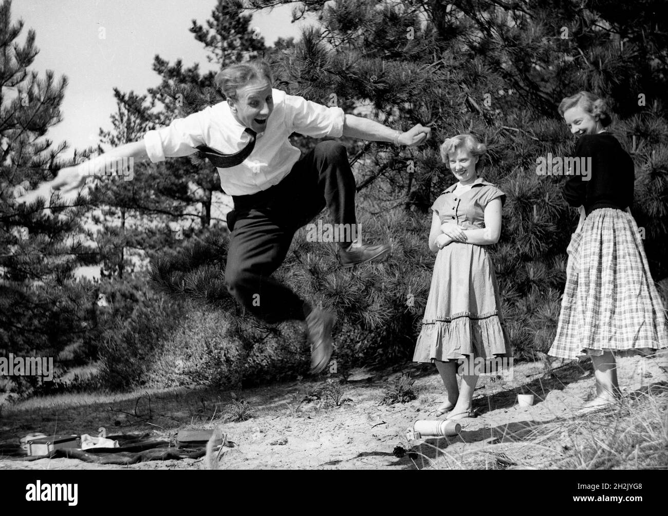 Joven impresionando a las chicas saltando en el aire Gran Bretaña 1950 Foto de stock