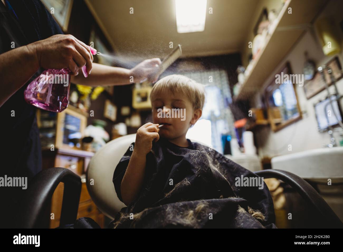 Niño pequeño disfrutando de un chupa durante un corte de pelo en una  peluquería Fotografía de stock - Alamy