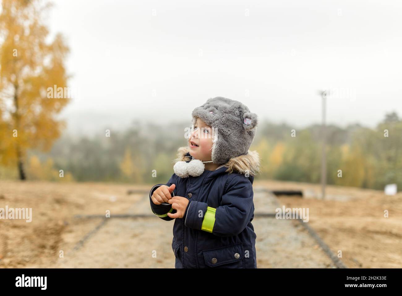 Niño pequeño con sombrero peludo mirando en la cima de una colina Foto de stock