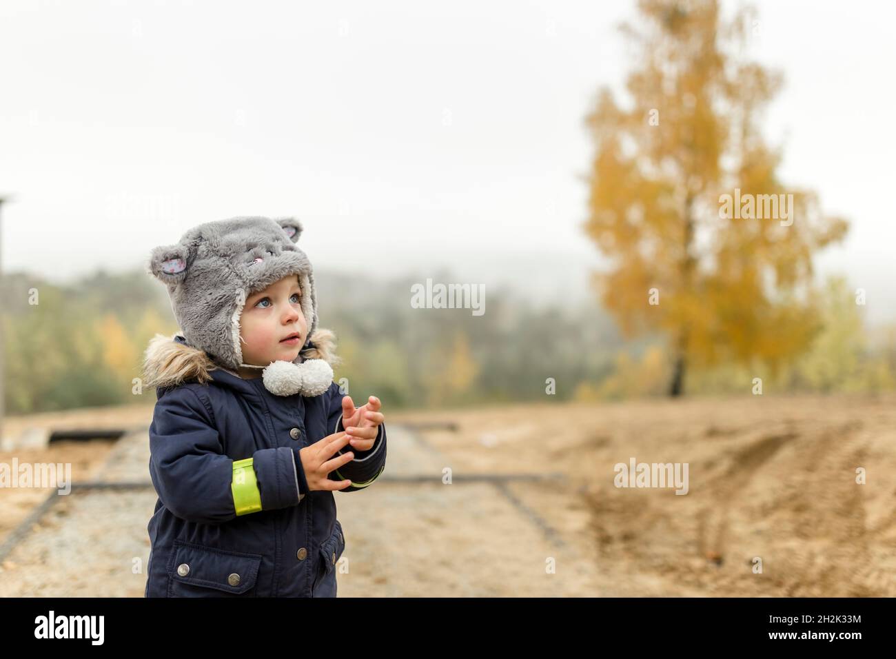 Niño pequeño con sombrero peludo mirando en la cima de una colina Foto de stock