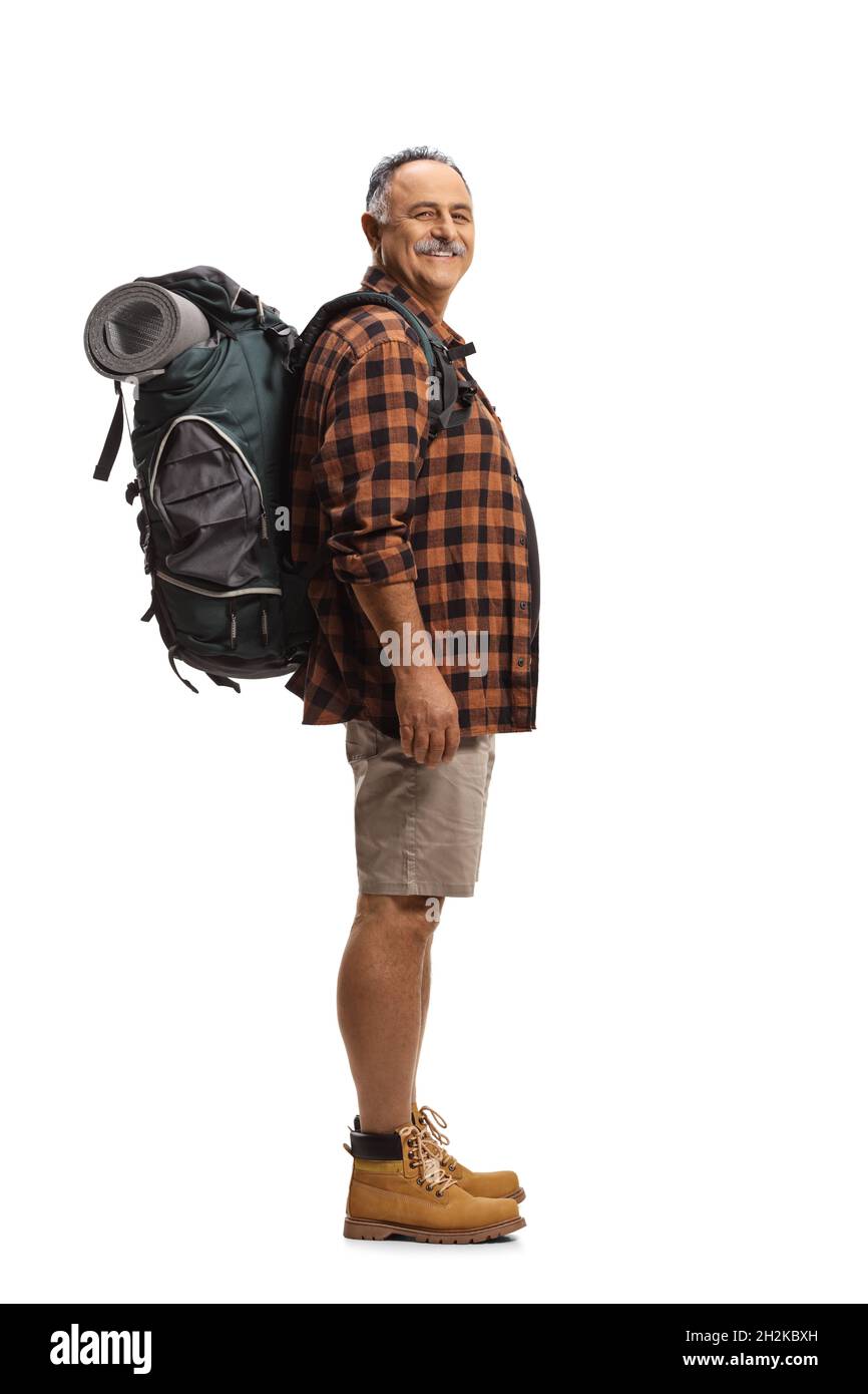 Alegre excursionista maduro con una mochila de pie y sonriente aislado sobre fondo blanco Foto de stock