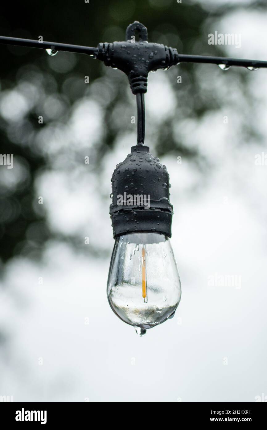Bistro cuerda luz cubierta de gotas de agua - húmedo fuera de comedor en el otoño / otoño - lluvia y poca luz Foto de stock
