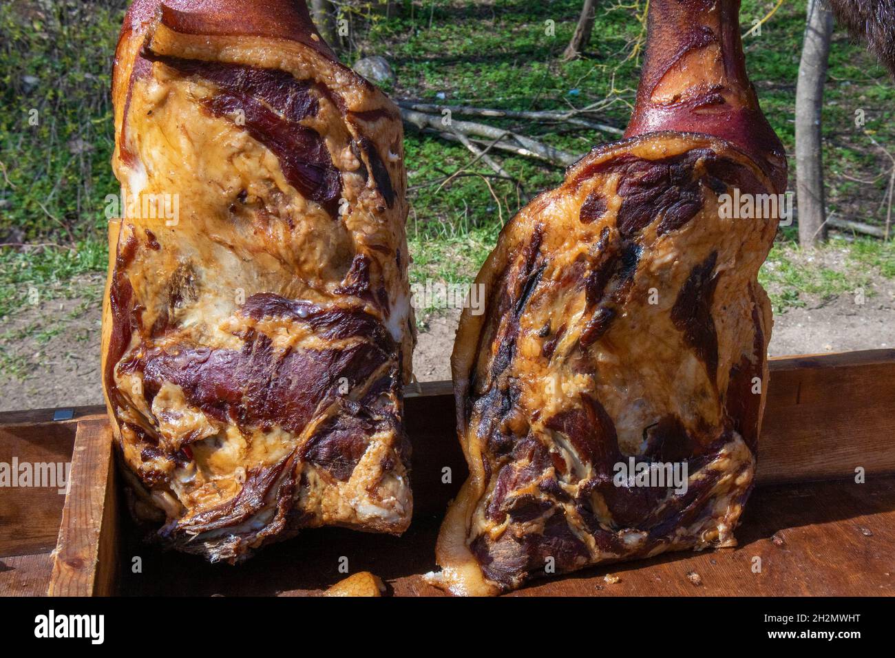Dos apetitosos jamones de cerdo ahumado caseros colgados sobre ganchos en la tienda de comercio justo del pueblo Foto de stock