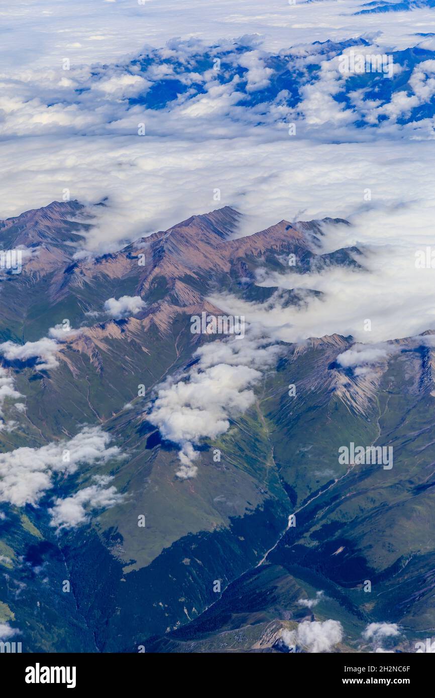 Vista aérea sobre las nubes y picos de montaña en una vista soleada day.mountain desde el avión. Foto de stock