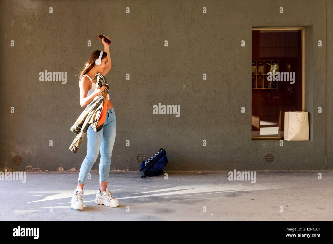 Adolescente mujer con auriculares inalámbricos bailando en el sendero Foto de stock