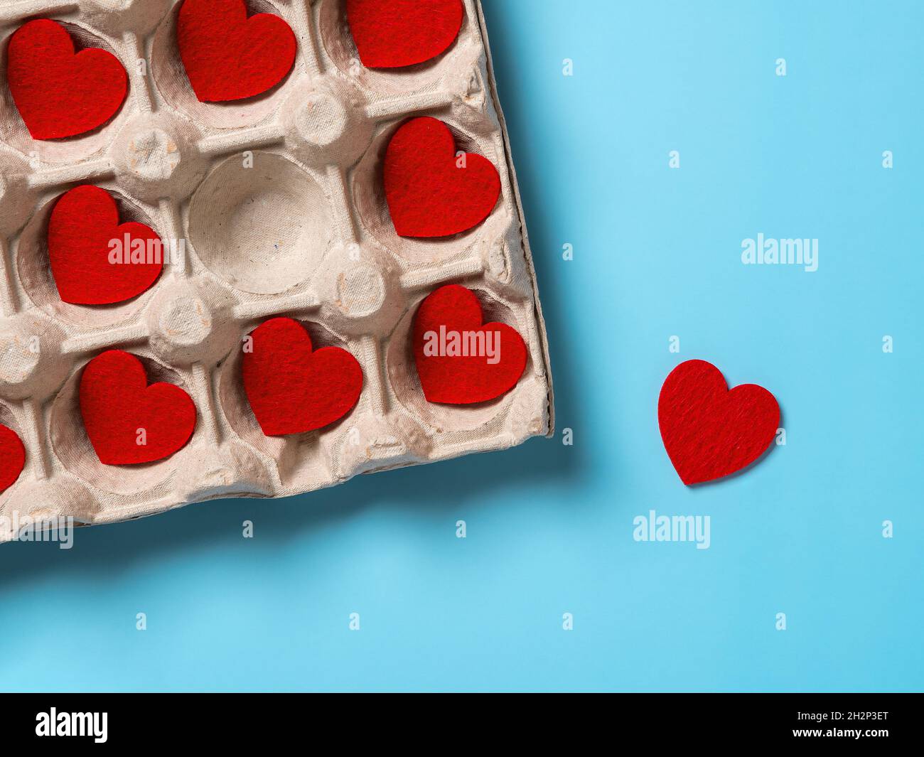 Un corazón de San Valentín sacado de la bandeja de cartón contra fondo turquesa. Romper a alguien corazón y conceptos descorazonador. Foto de stock