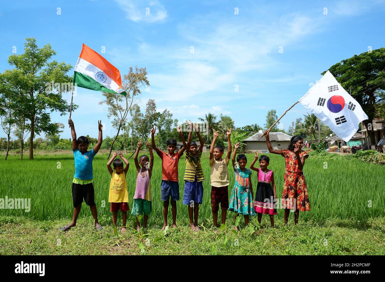 Los niños rurales están albergando una colorida bandera que representa a dos países diferentes bandera simbólica y teniendo un tiempo de diversión juntos en la aldea remota. Foto de stock