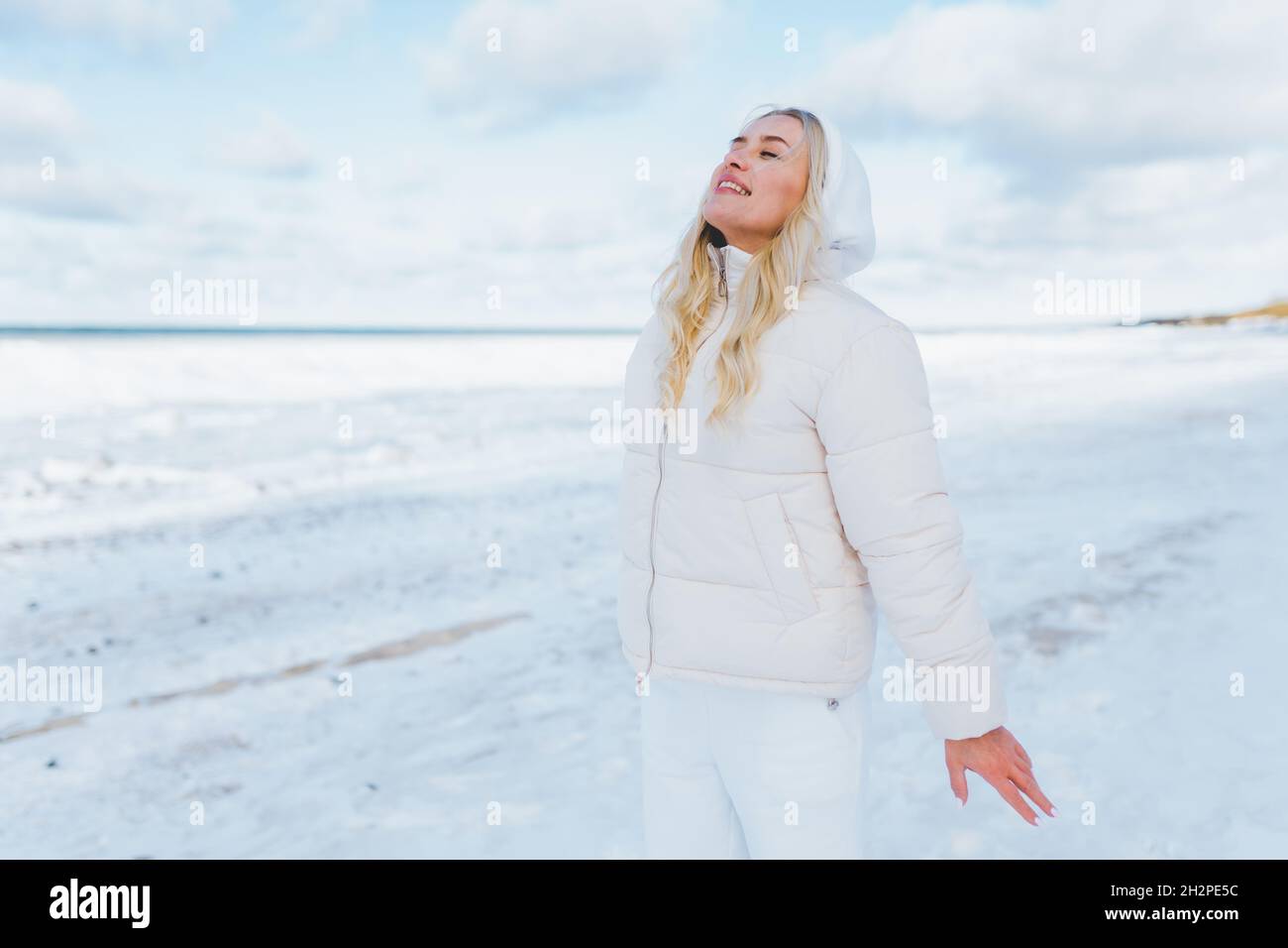 La mujer que lleva ropa blanca siente el frío en la costa de invierno. Las mujeres respiran con fresco y frío Fotografía de stock - Alamy