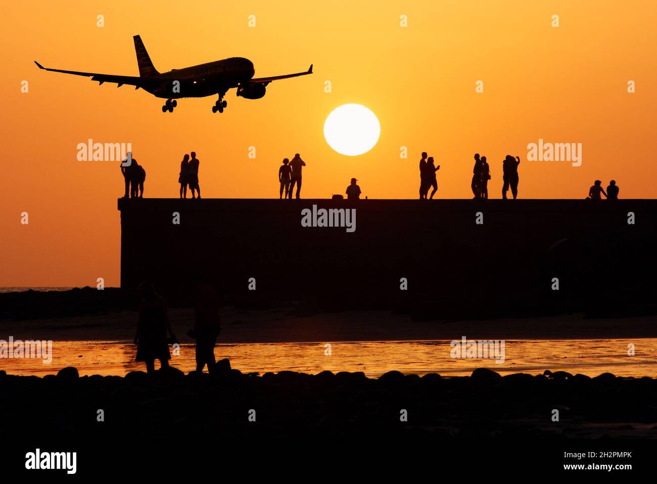 Turistas viendo puesta de sol con avión, aviones volando bajo. Turismo, industria de la aviación, contaminación del aire, calentamiento global, cambio climático... concepto Foto de stock