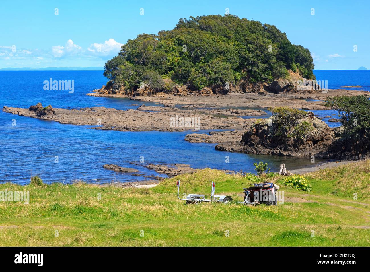 Costa en Little Awanui en el Cabo Este de Nueva Zelanda. Justo frente al mar está la Isla Motunui. Aparcado en el césped hay una quad bike Foto de stock