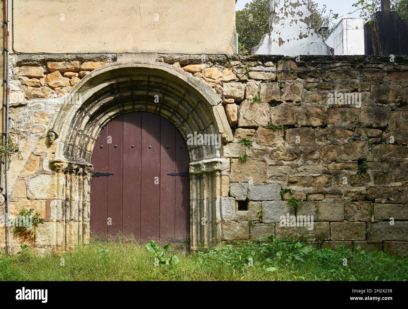 Puerta románica en una pared de piedra rústica. Foto de stock