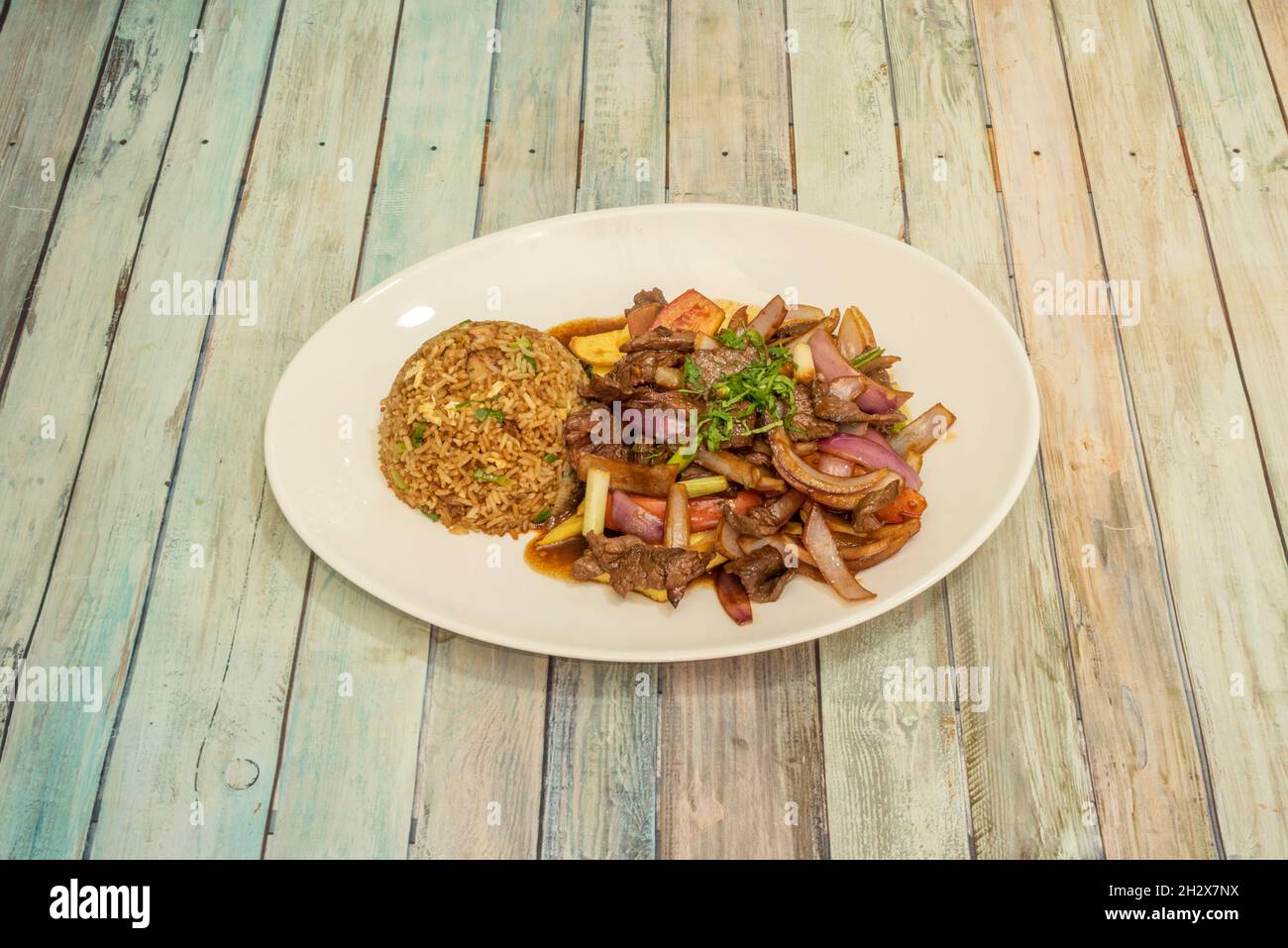 Bandeja de recetas de lomo saltado peruano con arroz chaufa, verduras, cebolla roja y perejil Foto de stock
