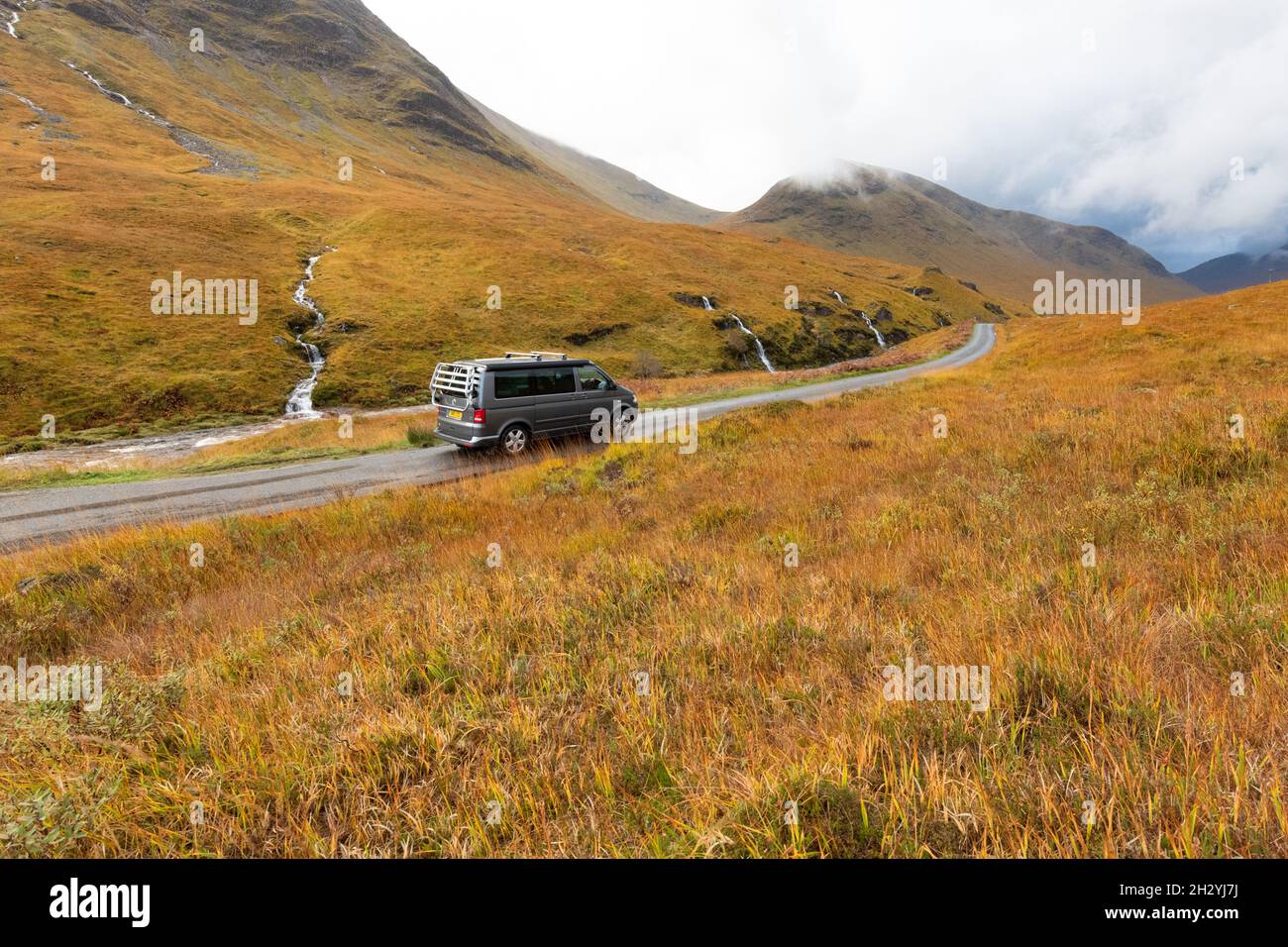VW Campervan conduciendo por Glen Etive en otoño, Escocia, Reino Unido Foto de stock