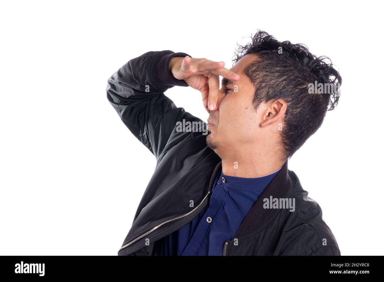 Hombre sosteniendo su nariz por mal olor. Fondo blanco. Joven adulto latino con expresión disgustada de mal olor. Foto de stock