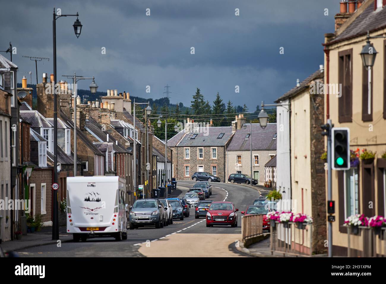 Lauder, en el escocés Boarders Escocia, A68 High Street pensó que el pueblo establecido en una restricción de velocidad de 20 mph, el coche rojo va lento, Foto de stock