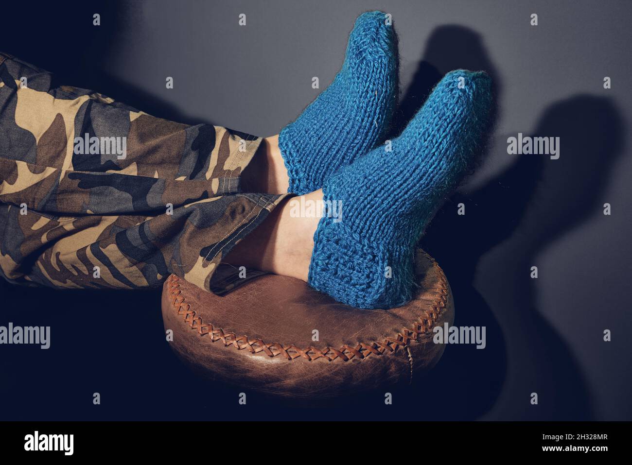 Pies de hombre en calcetines de lana sobre taburete Foto de stock