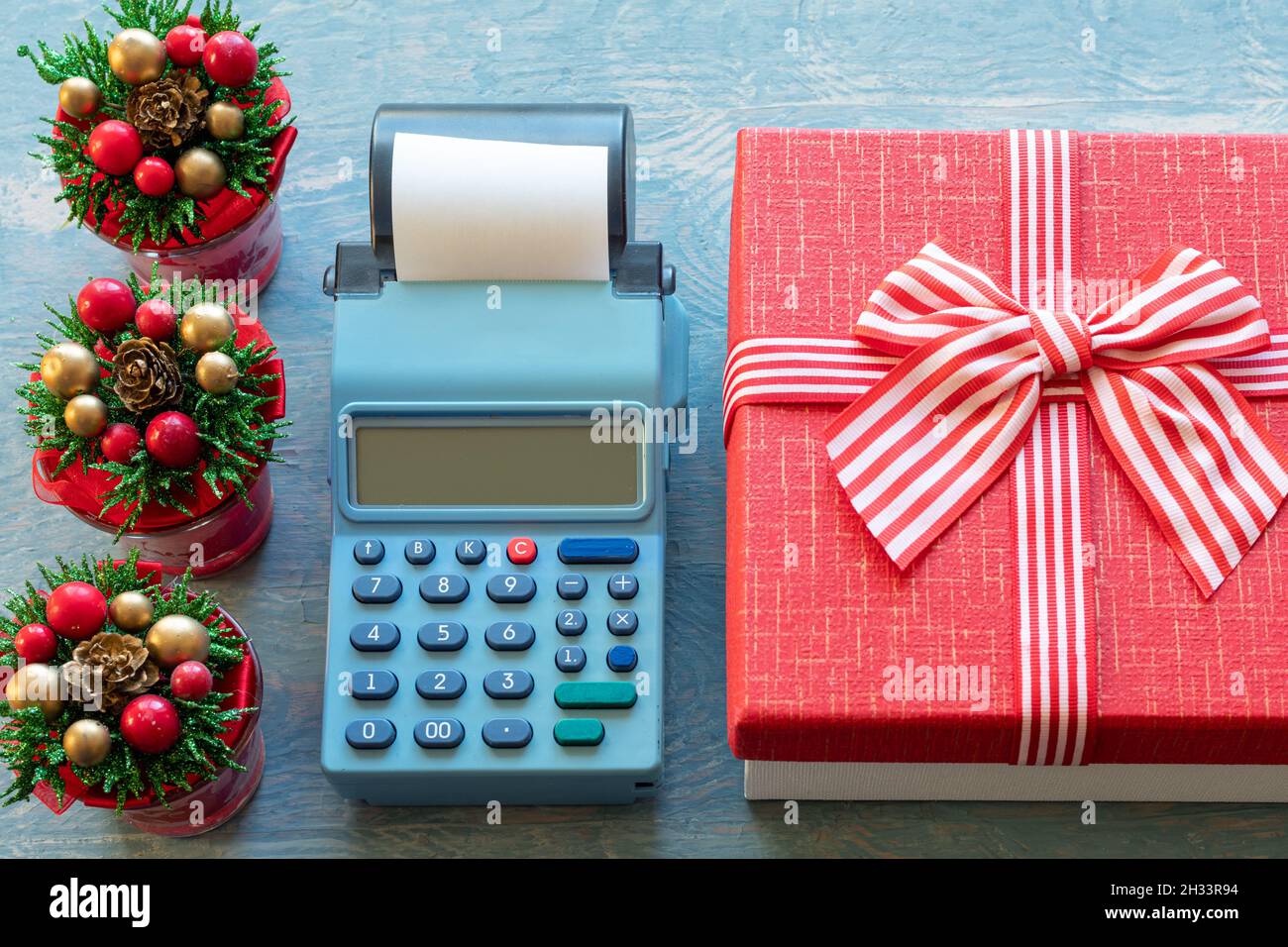Rebajas de Navidad. Caja de efectivo, caja de regalo roja con cinta y  pequeños árboles de Navidad con conos, primer plano, vista superior.  Comprar regalos para el Año Nuevo y Cristo Fotografía