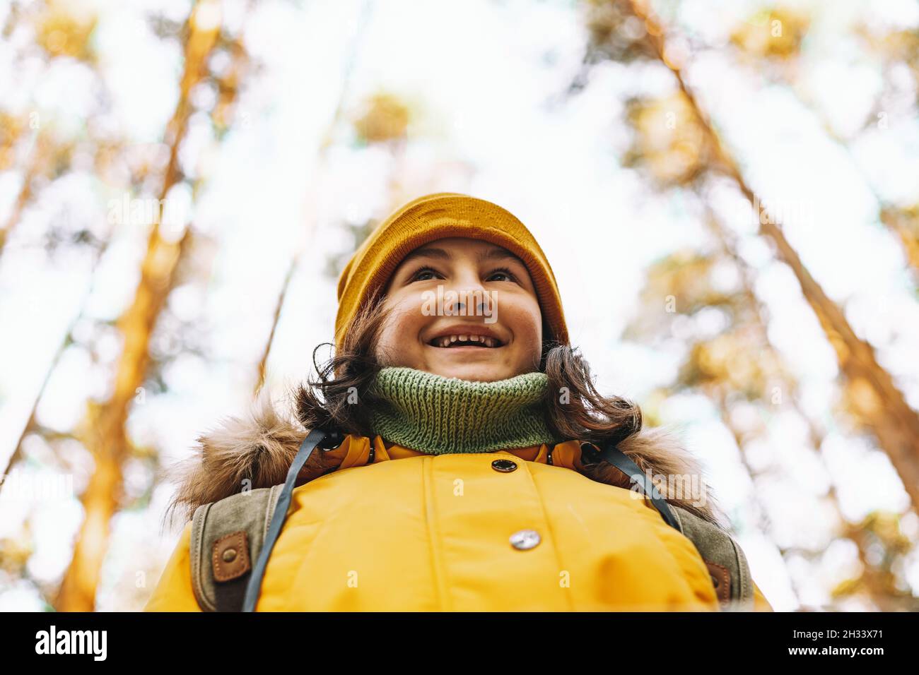 Retrato de una alegre niña de turistas caucásicos con una chaqueta y un sombrero de color naranja. Senderismo en el bosque de otoño. Emociones positivas. Actividades al aire libre. Senderismo Foto de stock