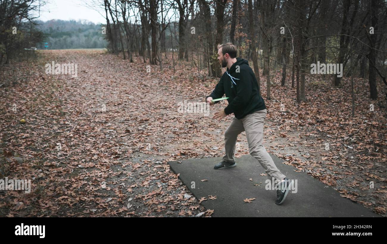 Atleta joven jugando al golf de disco en el bosque durante el invierno Foto de stock