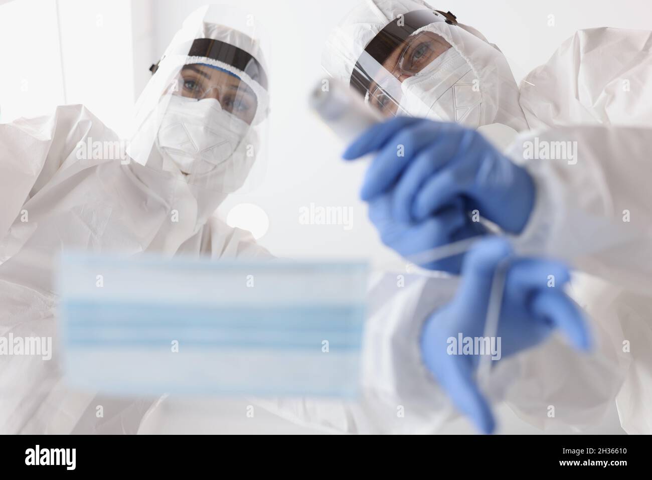 Médico en trajes médicos de protección poniendo la máscara en el paciente y mide la temperatura de la vista inferior Foto de stock