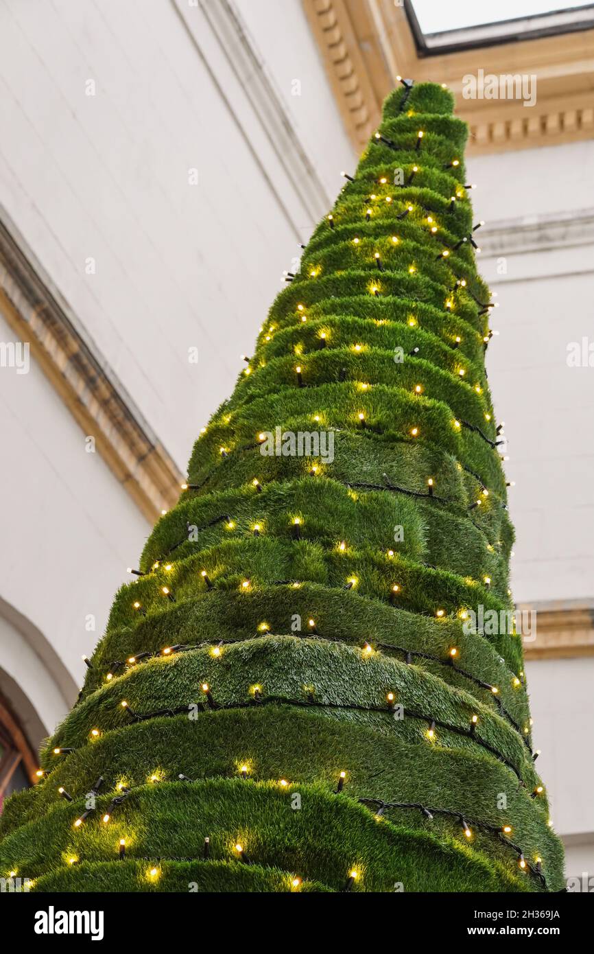 Árbol de Navidad inusual hecho de césped artificial decorado con guirnaldas  doradas. Enfoque selectivo Fotografía de stock - Alamy