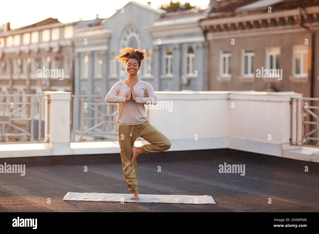 Foto recortada de mujer sentada en la pose de loto en la colchoneta y practicando yoga, mujer haciendo gesto namaste mientras meditaba en el interior. Meditación y mindfu Foto de stock