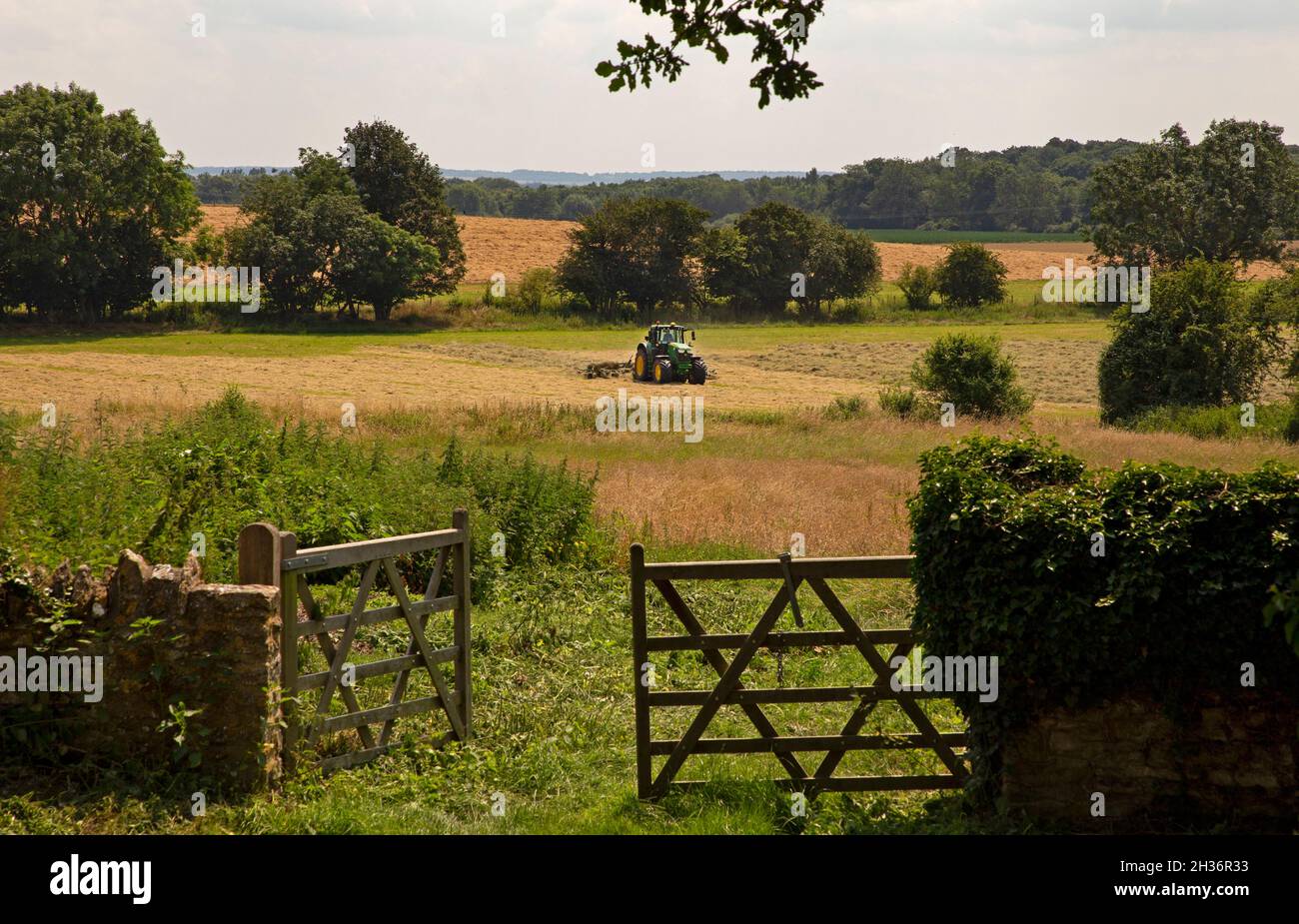 Tractor en campo de secado de heno en prado, oxfordshire, inglaterra Foto de stock