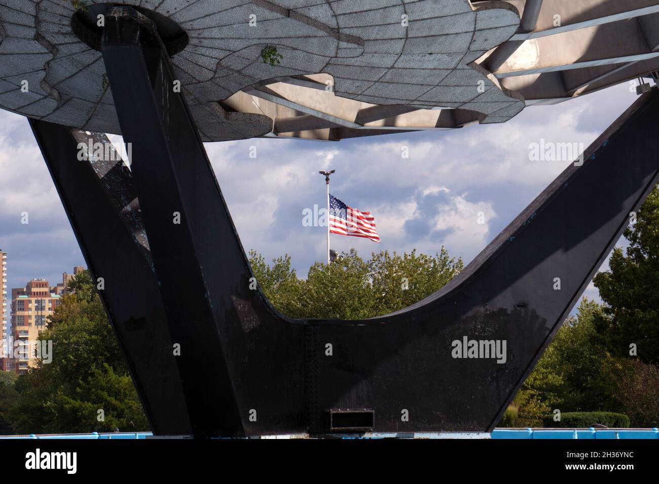Una bandera estadounidense vista a través de Unisphere en Flushing Meadows Corona Park en Queens, Nueva York. Foto de stock
