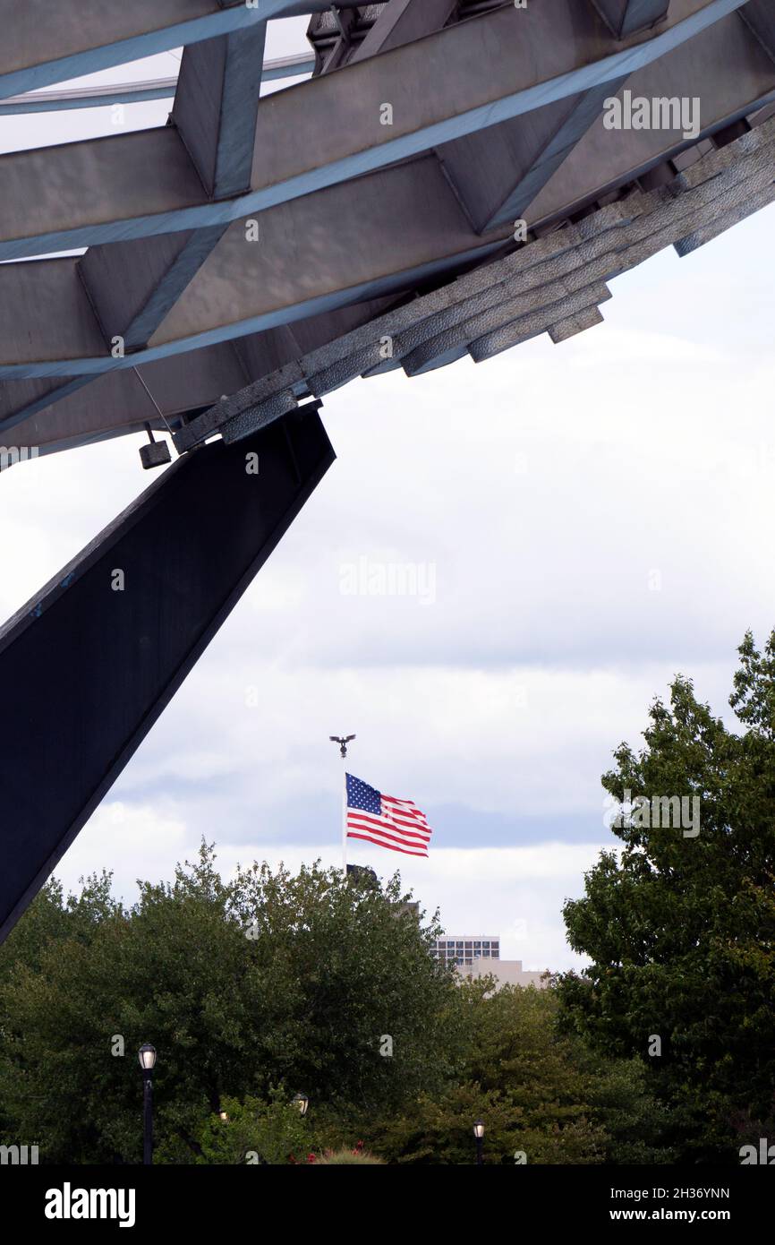 Una bandera estadounidense vista a través de Unisphere en Flushing Meadows Corona Park en Queens, Nueva York. Foto de stock
