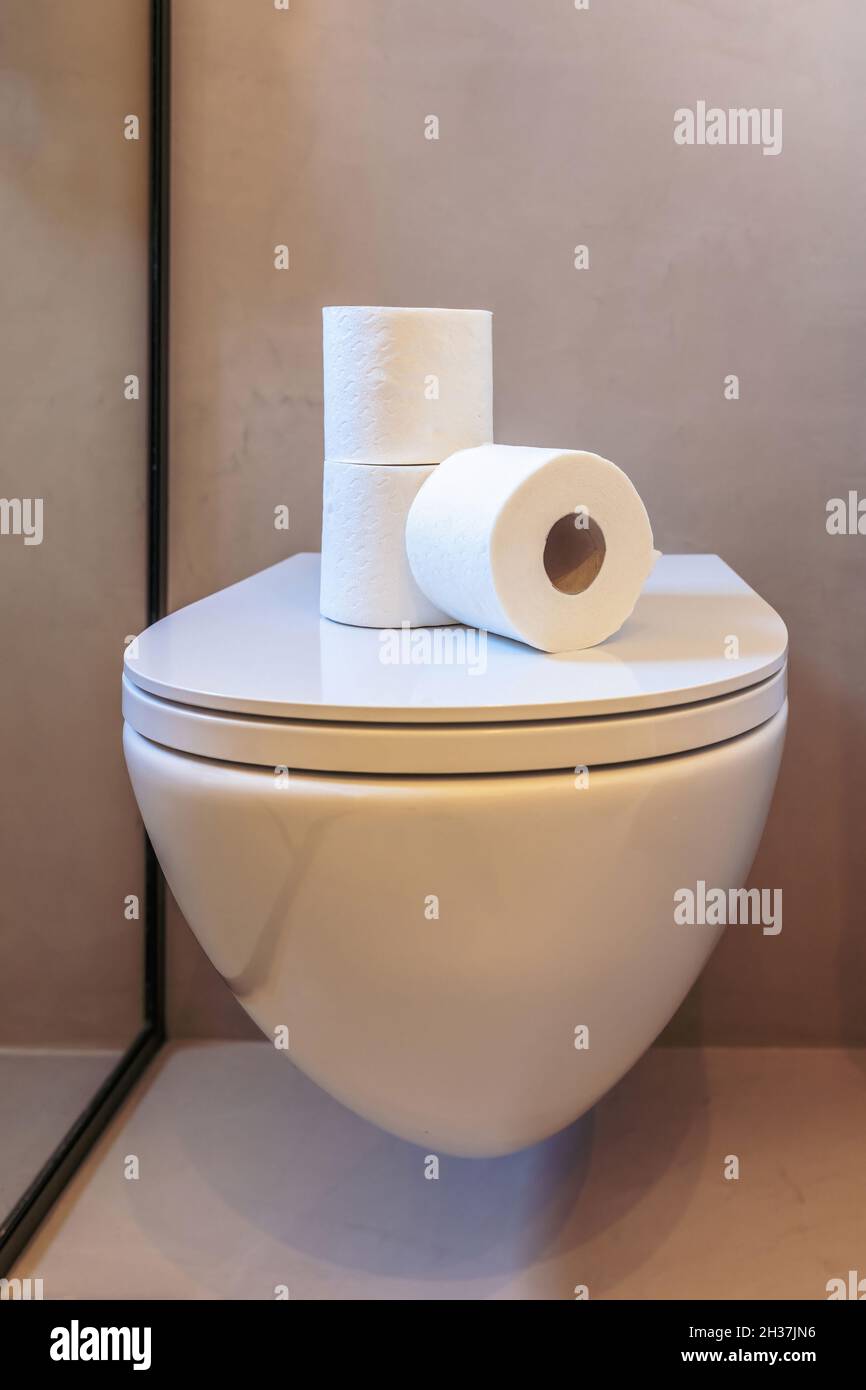 Rollos de papel higiénico. Tres servilletas de tejido blanco de higiene  apiladas sobre la tapa del recipiente del inodoro. Baño moderno con  detalles interiores Fotografía de stock - Alamy