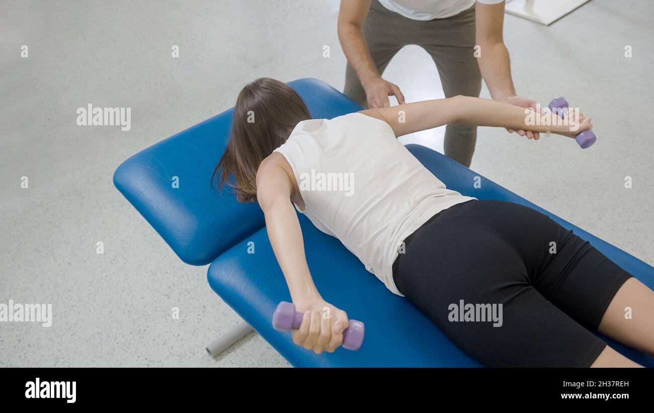 Mujer haciendo ejercicios de estabilización de hombro con pesas pequeñas,  con la ayuda del fisioterapeuta masculino Fotografía de stock - Alamy
