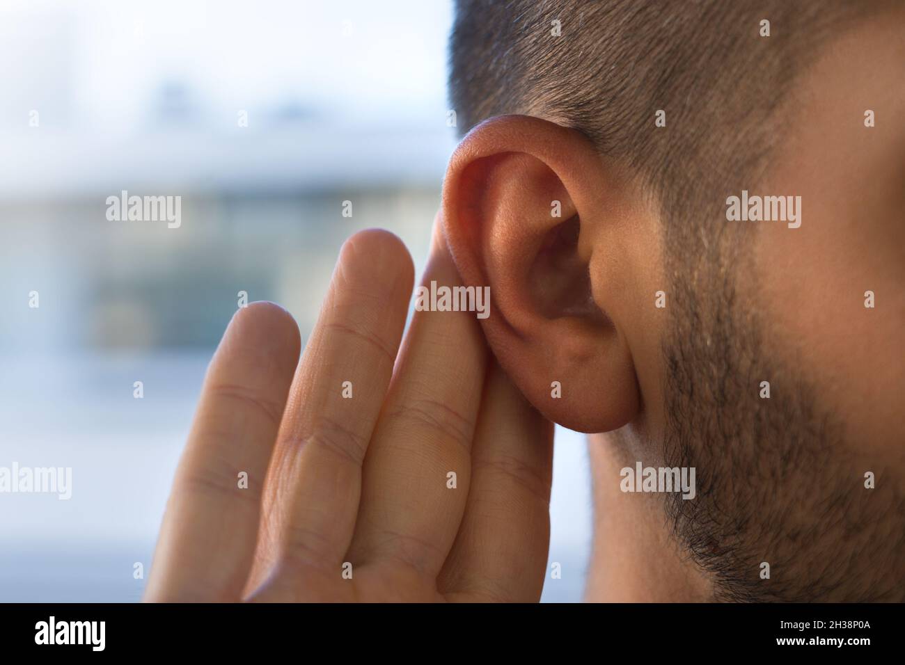 Hombre joven con problemas de audición, pérdida de audición o dificultad de audición Foto de stock