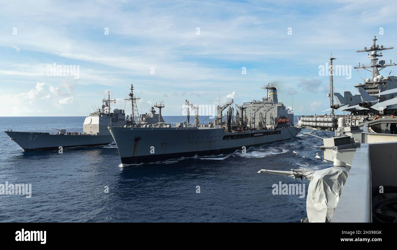 211026-N-OL611-1167 MAR DEL SUR DE CHINA (OCT 26, 2021) El buque de carga seca de clase Lewis y Clark USNS Matthew Perry (T-AKE 9) conduce un reabastecimiento en el mar con el portaaviones de clase Nimitz USS Carl Vinson (CVN 70) y el crucero de misiles guiados de clase Ticonderoga USS Lake Champlain (CG 57), 26 de octubre de 2021. Carl Vinson Carrier Strike Group está en un despliegue programado en el área de operaciones de la Flota de EE.UU. 7th para mejorar la interoperabilidad a través de alianzas y asociaciones, al tiempo que sirve como una fuerza de respuesta en apoyo de una región libre y abierta del Indo-Pacífico. (EE.UU Foto de la Marina por Especialista en Comunicación de Masas Foto de stock