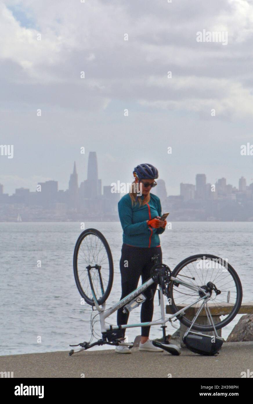 Ciclista en teléfono celular repara bicicleta en viaje a Sausalito Ca usa Foto de stock