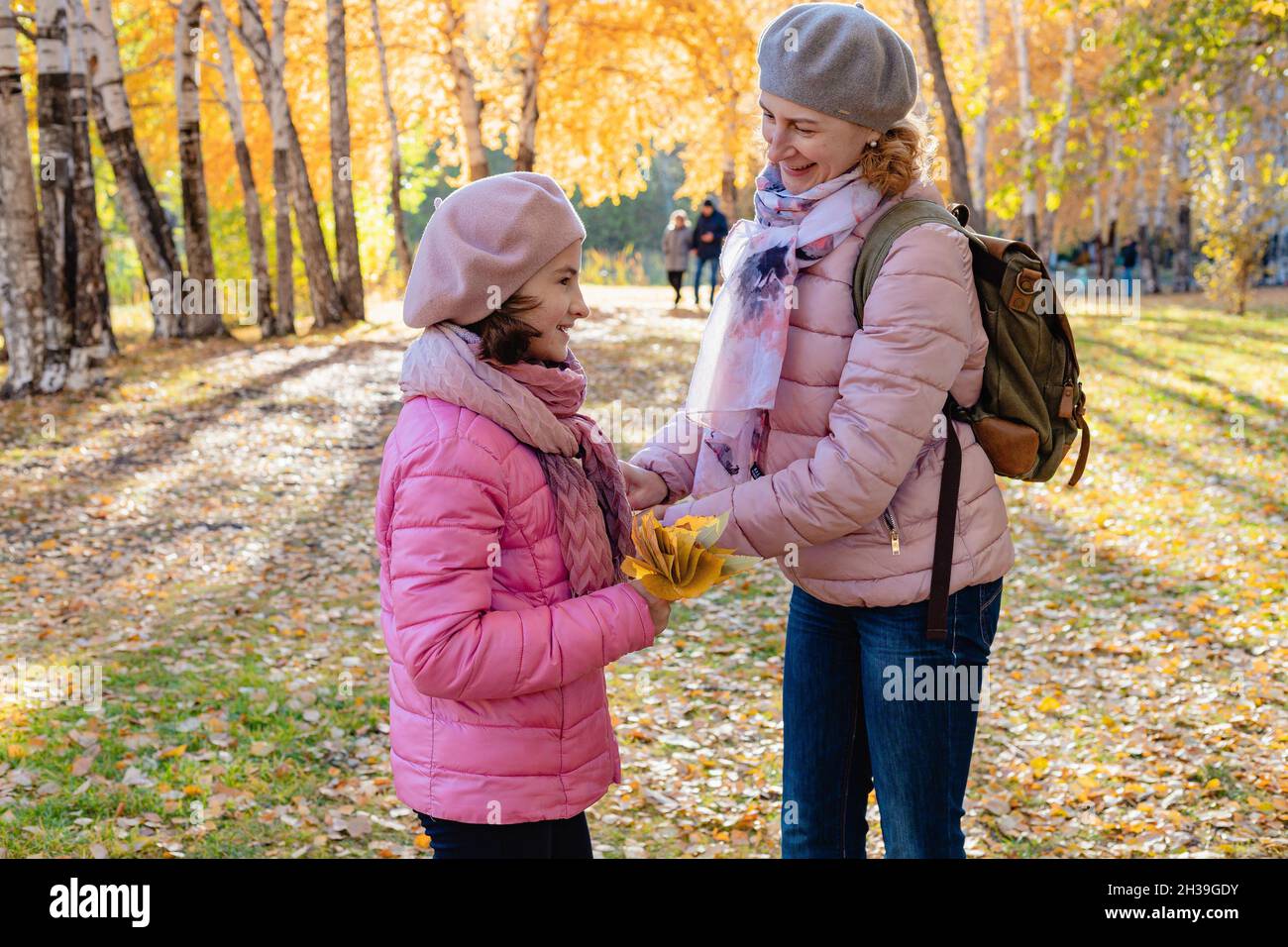 Caminar en el parque con niños. Mamá e hija caucásica sonriente, linda y alegre, pasan tiempo en el parque de otoño. Soleado día de otoño. Una familia feliz. P Foto de stock