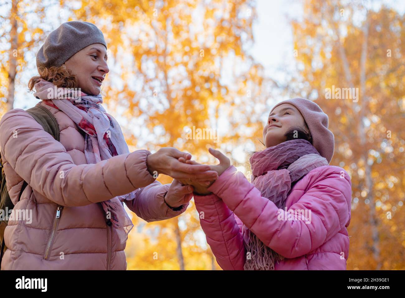 Mamá e hija caucásica sonriente, linda y alegre, pasan tiempo en el parque de otoño. Caminar en el parque con niños. Soleado día de otoño. Una familia feliz. P Foto de stock