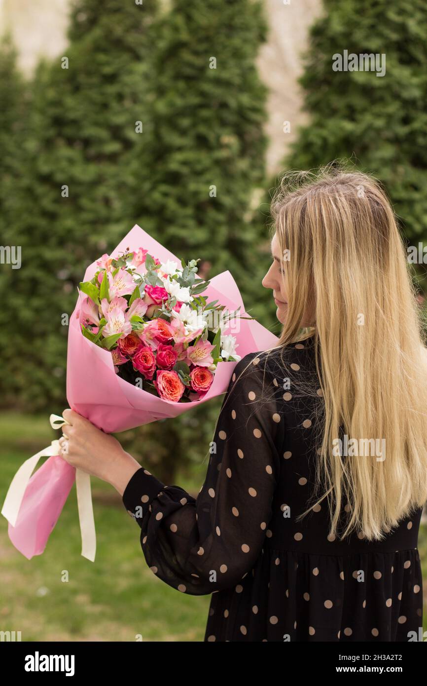 Hermosa niña sostener y caminar con ramo de flores después de la entrega en  la ciudad. Vista lateral. Concepto de personas reales Fotografía de stock -  Alamy