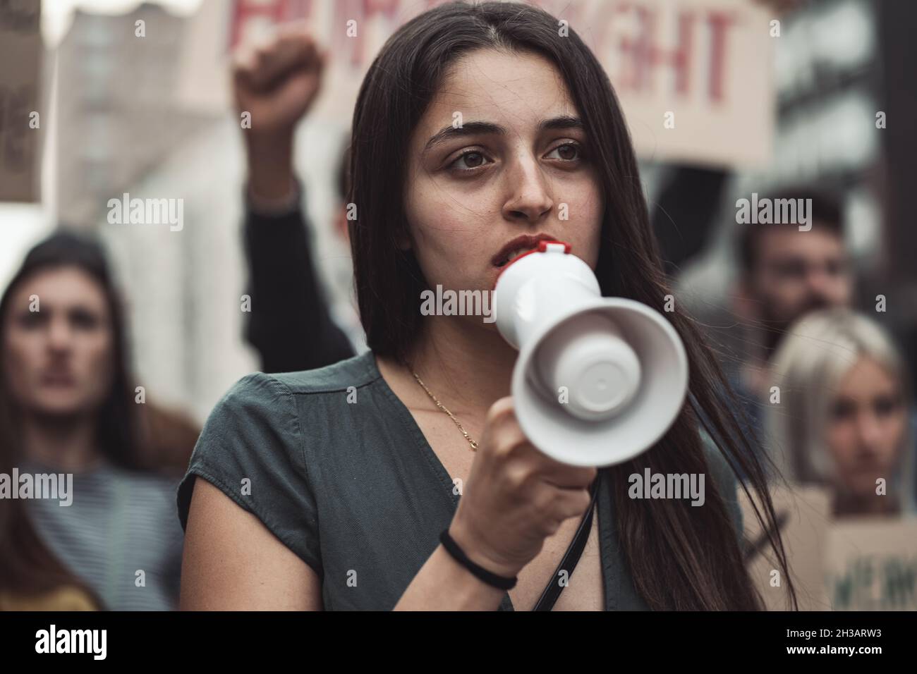 Retrato de una activista en una marcha de protesta con un megáfono con cuervos detrás de ella Foto de stock