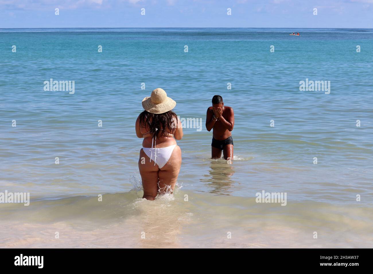 Pareja interracial en una playa, mujer blanca con sobrepeso y su novio negro en el agua del mar Foto de stock