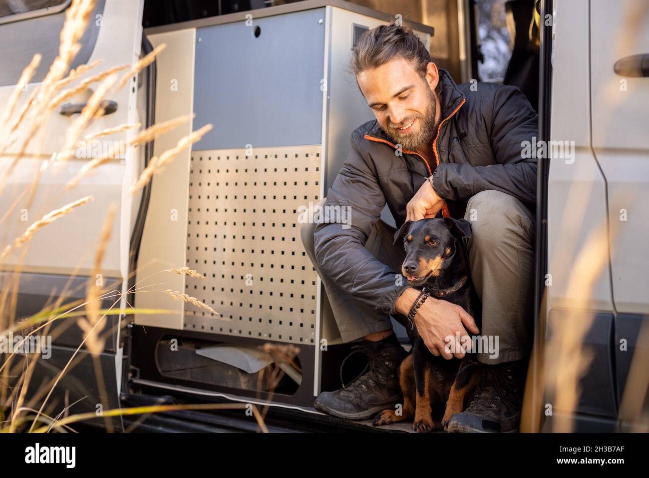 Hombre y su perro mascota sentados en la puerta de una camioneta Foto de stock