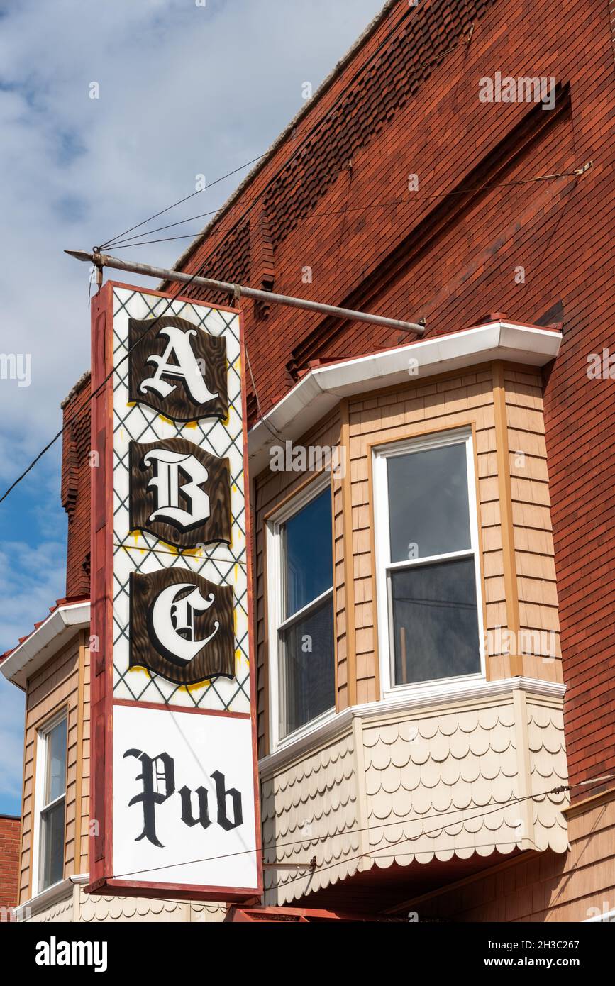 Un gran letrero blanco y negro para el ABC Pub, escrito en letra inglesa antigua, cuelga de un edificio de ladrillo con ventanas de bahía y madera decorativa festoneada. Foto de stock