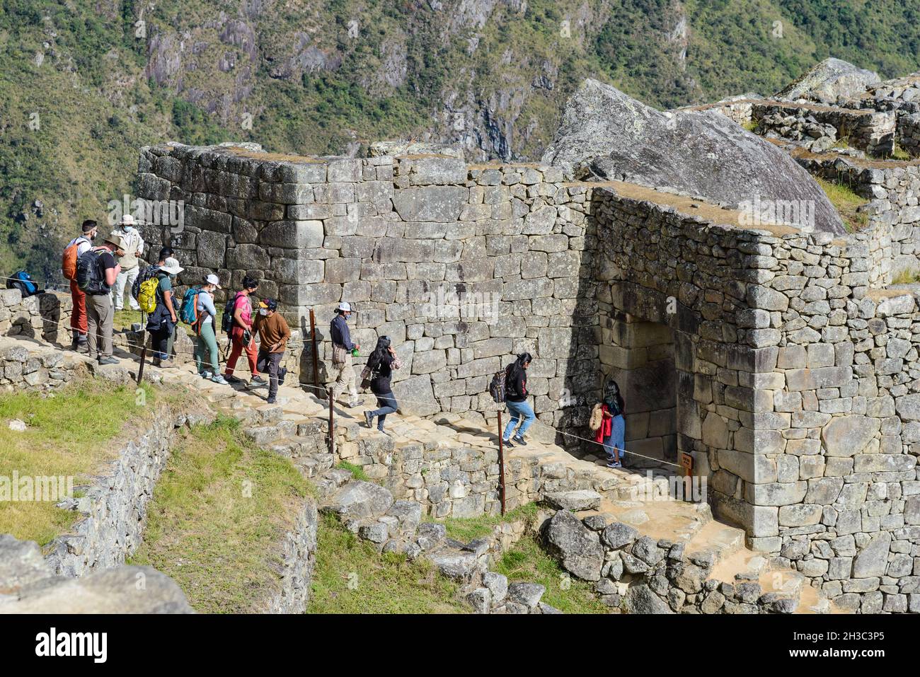Los turistas caminan por las escaleras de piedra para entrar en la puerta de la ciudad. Machu Picchu, Cuzco, Perú. Foto de stock